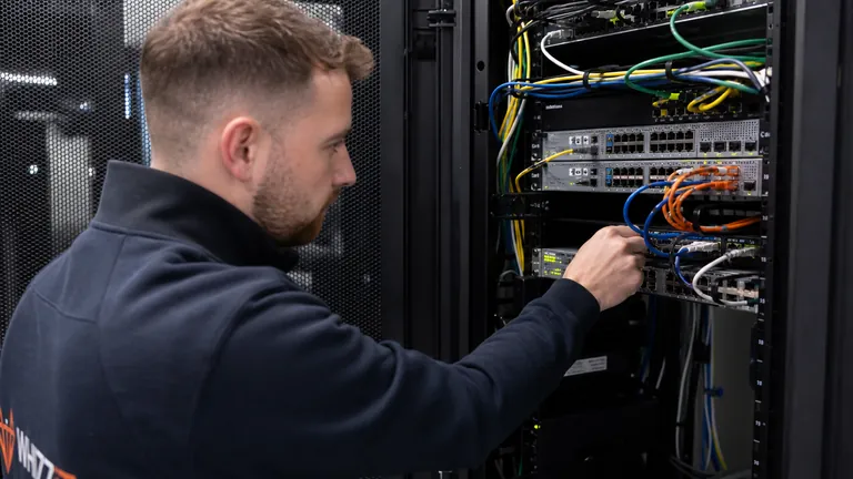 A WhizzIT network engineer connecting patch cables in a server rack