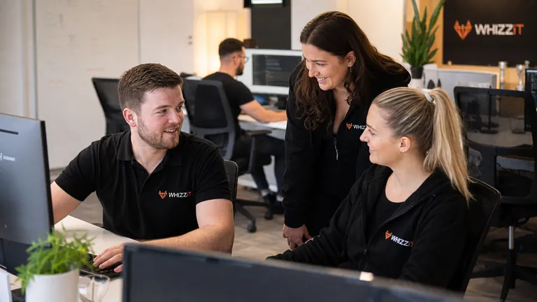 Colleagues in branded tops reviewing work together at a desk