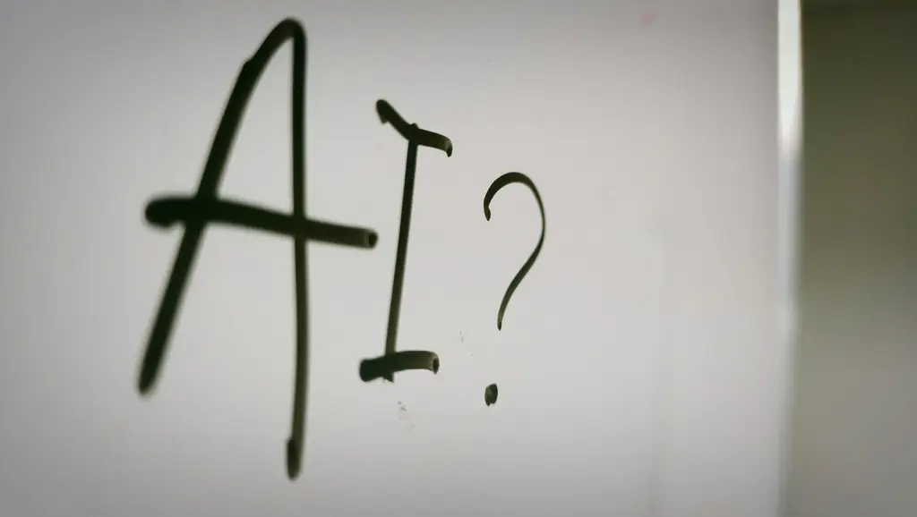 The letters AI and a question mark handwritten on a whiteboard