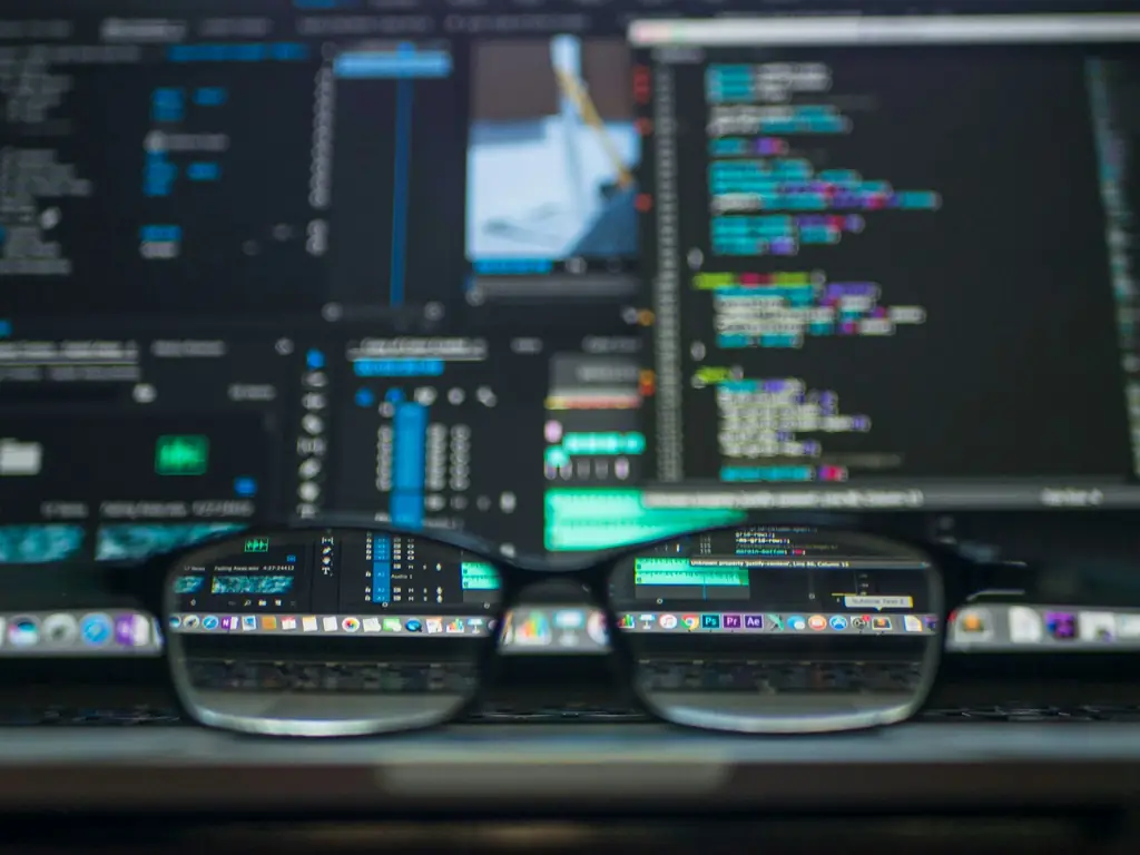 Glasses resting in front of monitors displaying code and settings