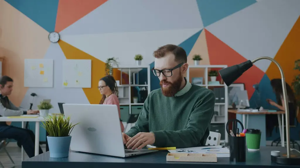 Man working on a laptop at his desk in a bright, colourful office