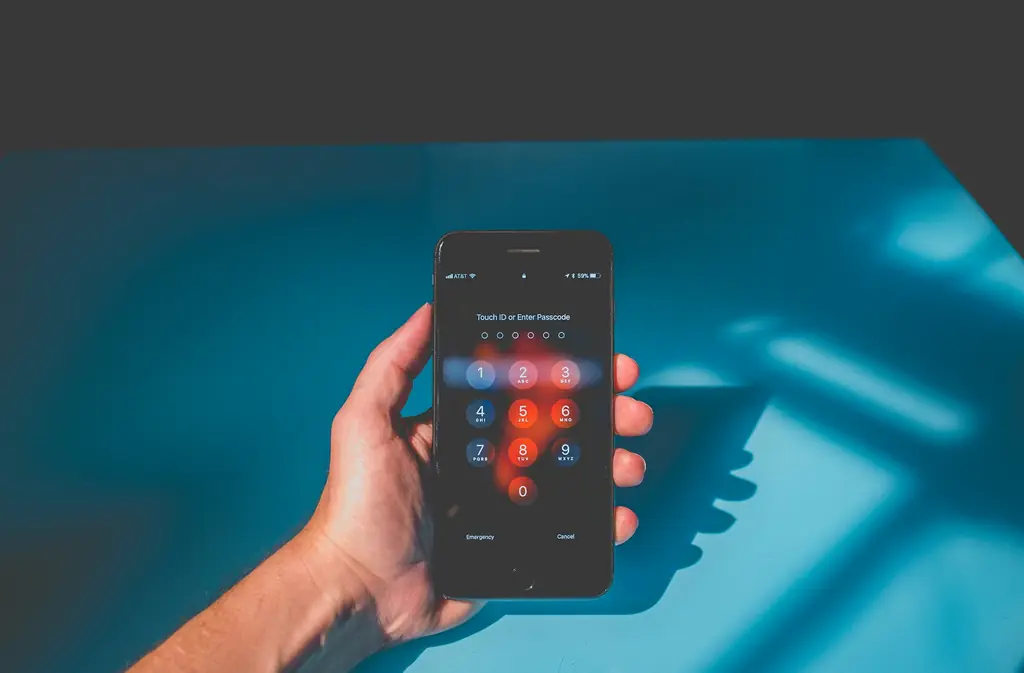 Hand holding a smartphone showing a Touch ID or passcode screen