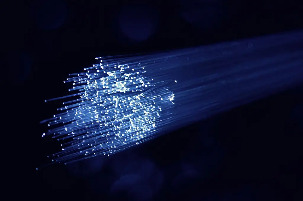 Bundle of glowing blue fibre optic strands on a dark background